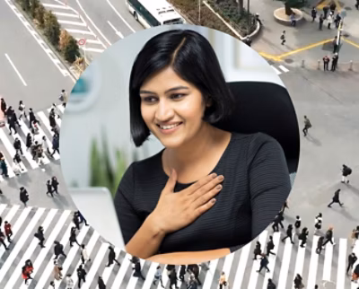 A women smiling and looking at a laptop.