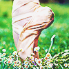 a pink ballet shoe en pointe in grass atop some flowers
