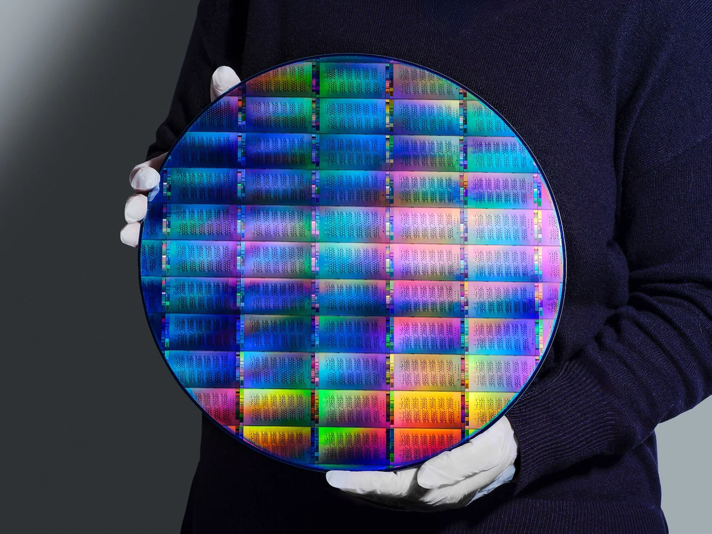 An IBM researcher with white gloves holds an IBM Quantum Nighthawk wafer.