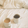 sarken: two mugs of coffee on a bed with white sheets ([misc] right next to her coffee)