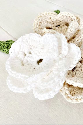 Crocheted white and cream flowers with pretty bright green leaves.